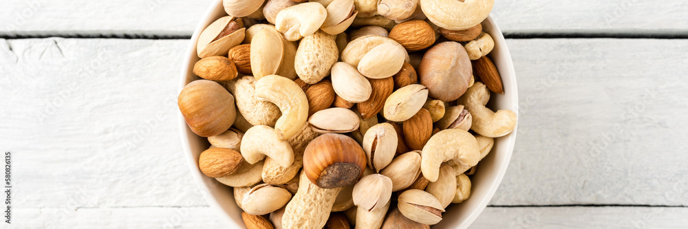 Mixed dried nuts (almonds, pistachios, peanuts, hazelnuts and cashews) in bowl on wooden table. Top view Mixed dried nuts (almonds, pistachios, peanuts, hazelnuts and cashews) in bowl on wooden table. Top view