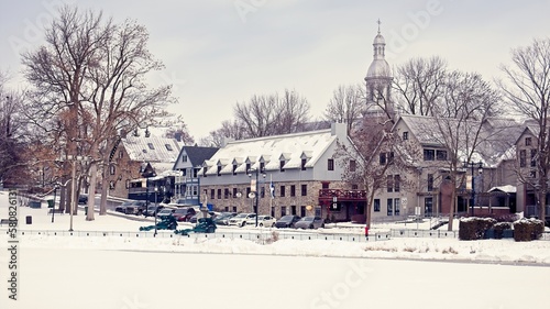 Winter scene city of Terrebonne with frozen pond, with buildings and church. 