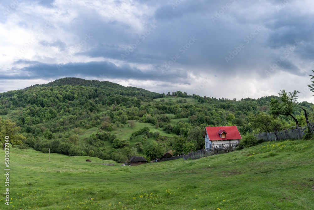 Landscape Nature in Romania. Mountains and Cloudy Sky. Lonely House with Red Roof