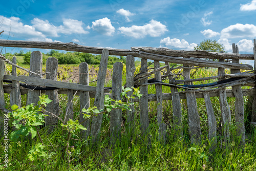 Old Wooden Fence in Rural Area. Green Grass and Blue Sky
