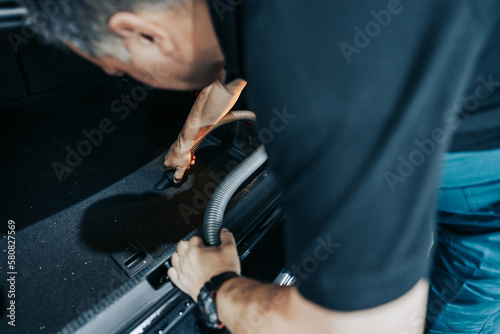 Professional worker cleaning car interior and trunk, car detailing (or valeting) concept. Selective focus. Ultra wide angle shot.