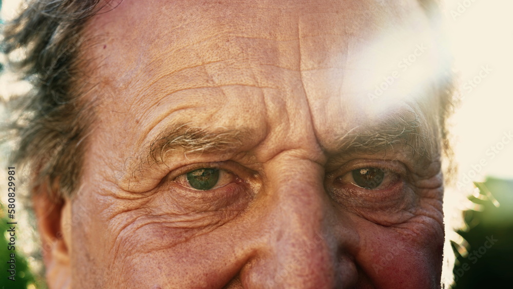 One senior person close up face and eyes with sunlight flare. Wrinkled elder mature 70s male person outside One senior person close up face and eyes with sunlight flare. Wrinkled elder mature 70s male person outside