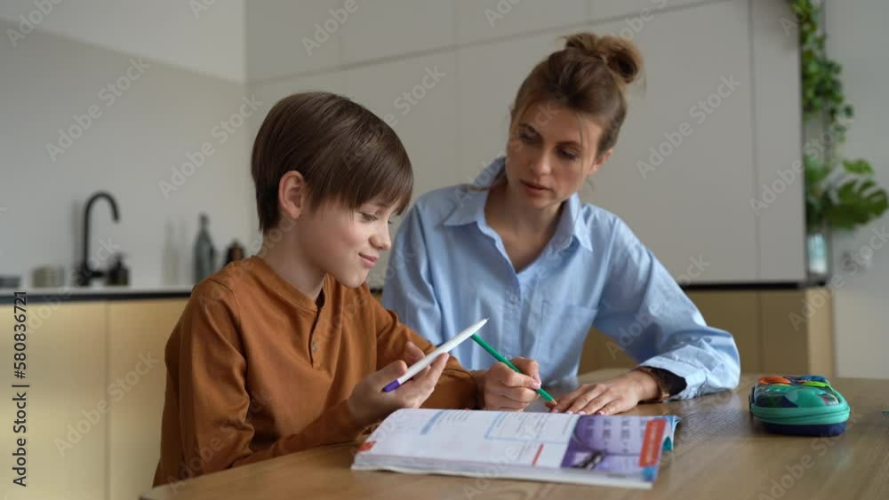 Parental involvement in education. School age boy child doing homework assignment with mother at home, mom explaining exercise to son, parent and kid having fun while studying together Parental involvement in education. School age boy child doing homework assignment with mother at home, mom explaining exercise to son, parent and kid having fun while studying together