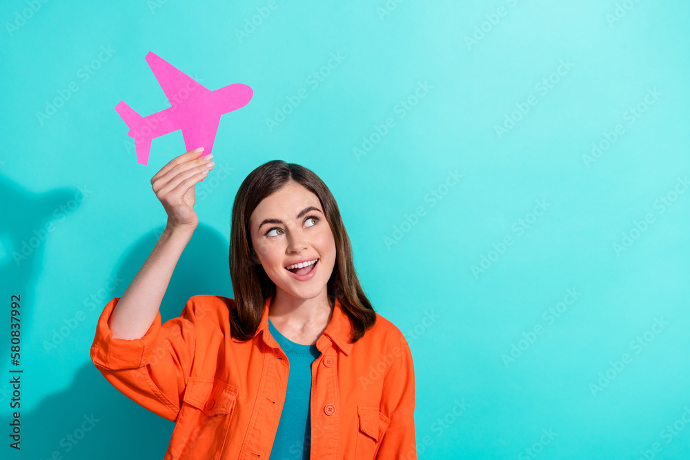 Photo of cheerful cute lady wear stylish orange clothes hold plane dream summer trip weekend empty space isolated on cyan color background Photo of cheerful cute lady wear stylish orange clothes hold plane dream summer trip weekend empty space isolated on cyan color background