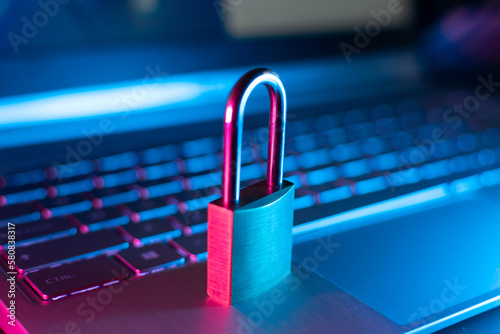 Cybersecurity and data privacy illustration with high-tech padlock protecting a laptop computer and electronic online information symbols/graphics