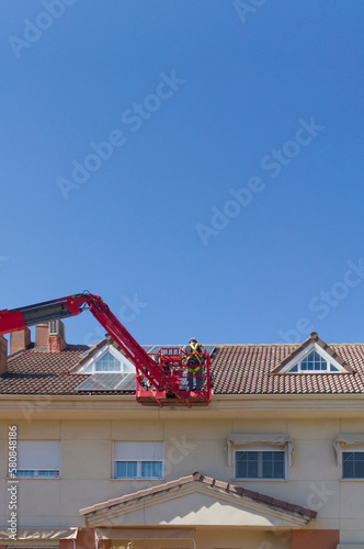 Workmen installing solar panels on the roof of a terraced house