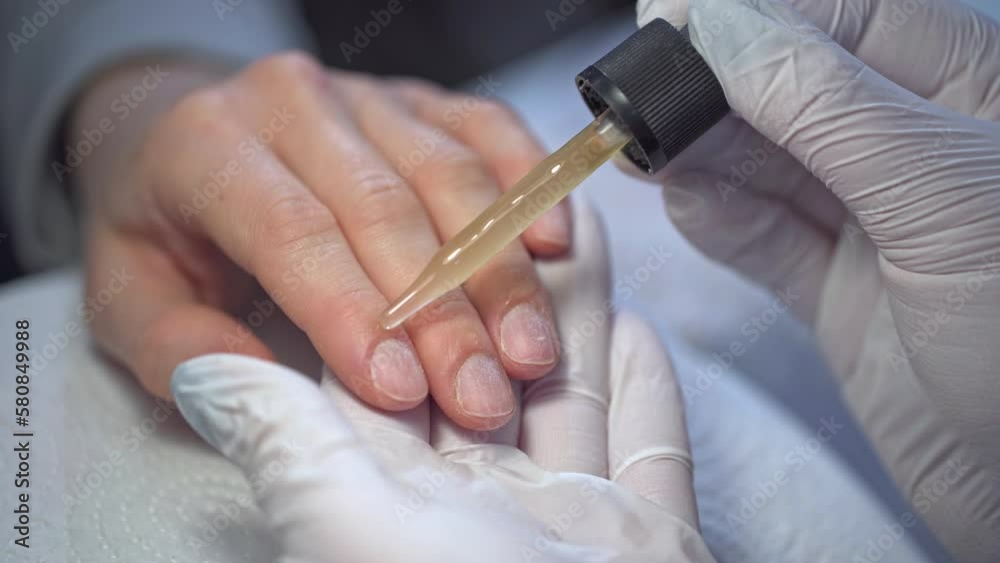 Manicurist applies cuticle oil to her client