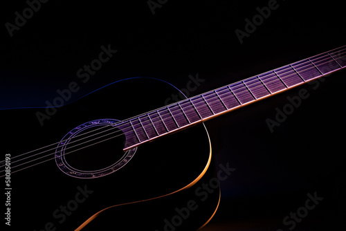 fragment of a black guitar against a dark background. guitar music low-key concept side view