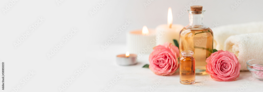 Aromatherapy. Pure organic essential rose oil concept. Elixir with plant based floral herbal ingredients. Pink flowers extract. Spa atmosphere with candle, towel. White background. Banner copy space - obrazy, fototapety, plakaty 