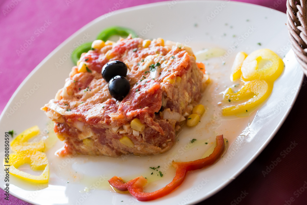 Mixed tomatoes and canned tuna - Timbale dish - served with peppers on plate
