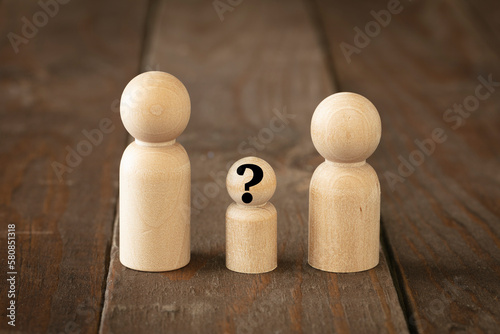 Childless couple thinking about adoption concept. Wooden figures simulate a couple thinking about the future of kids enlarge the family on brown wood surface.
