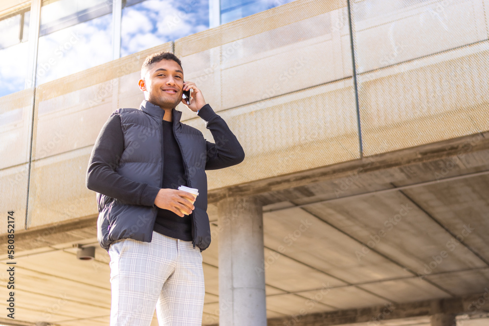 smiling young latin man corporate executive talking on cellphone looking at camera smiling young latin man corporate executive talking on cellphone looking at camera