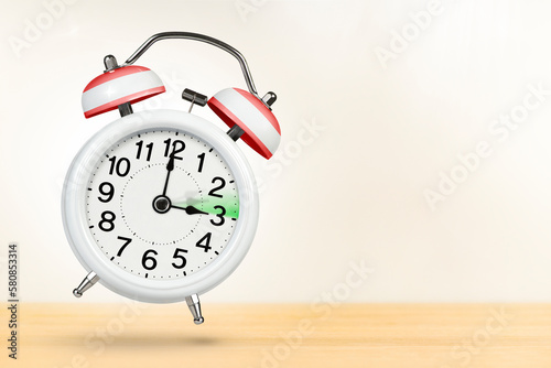 Time change in Austria, spring forward. Summer time concept, over white background. A white alarm clock with a minute hand indicates that the time has been moved forward an hour with copy space.