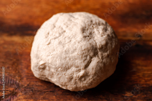Yeast dough ball on wooden background. Cooked dough for baking pizza or bread.