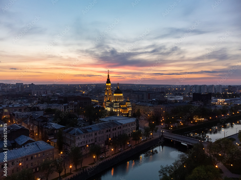 Holy Annunciation Cathedral with lights illumination and evening sunset vivid cloudscape. Aerial Kharkiv city orthodox church in downtown, Ukraine
