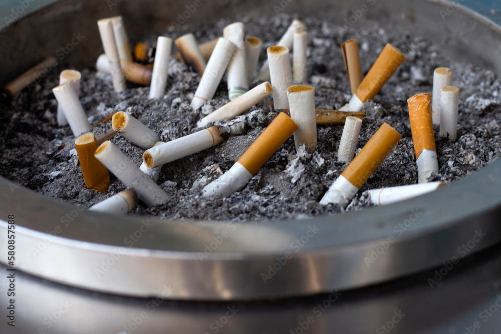 Cigarettes and ash on dirty sand in trash tray Cigarettes and ash on dirty sand in trash tray