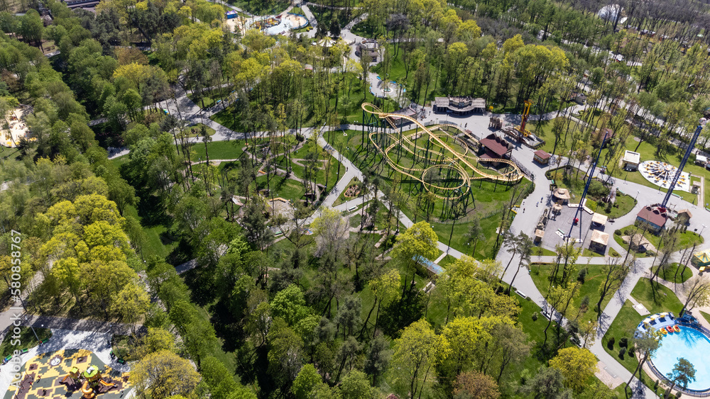 Attractions recreation area and playgrounds in spring greenery. Aerial look down view in Kharkiv city central amusement park