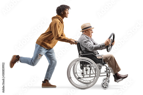 Full length profile shot of a young african american man pushing a mature man in a wheelchair holding a steering wheel