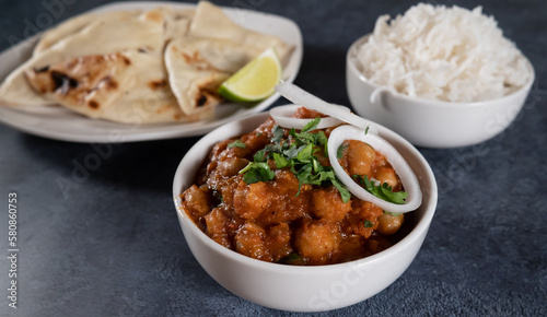 Indian chena masala or chole masala served in a traditional way along with Naan and white rice