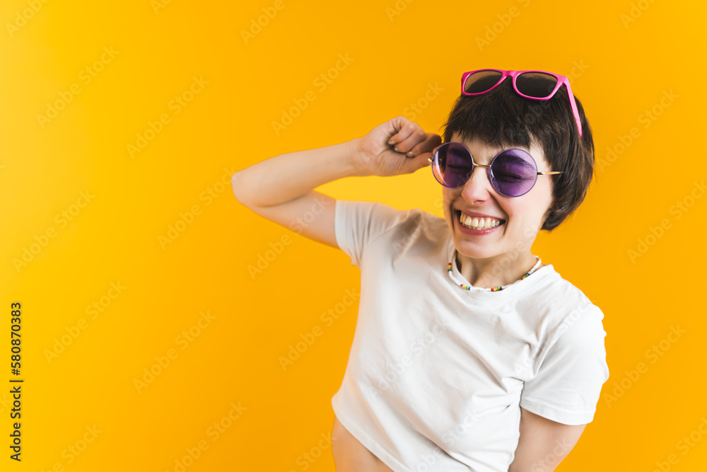 Smiling woman in two pairs of sunglasses. Bright orange background. Happiness concept. High quality photo Smiling woman in two pairs of sunglasses. Bright orange background. Happiness concept. High quality photo