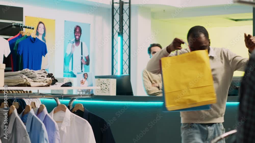 Funny happy person dancing after buying merchandise, leaving with shopping bags from cash register and feeling cheerful. Male smiling client doing dance moves acting silly in retail store. Funny happy person dancing after buying merchandise, leaving with shopping bags from cash register and feeling cheerful. Male smiling client doing dance moves acting silly in retail store.
