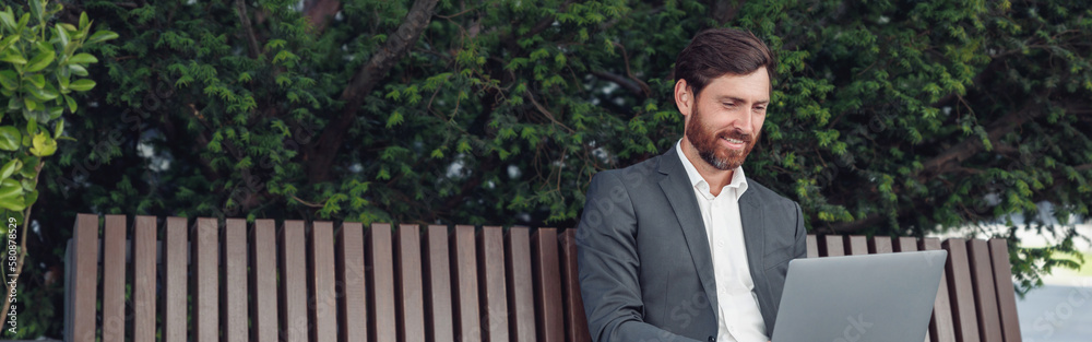 Business man office worker working on laptop in urban park background