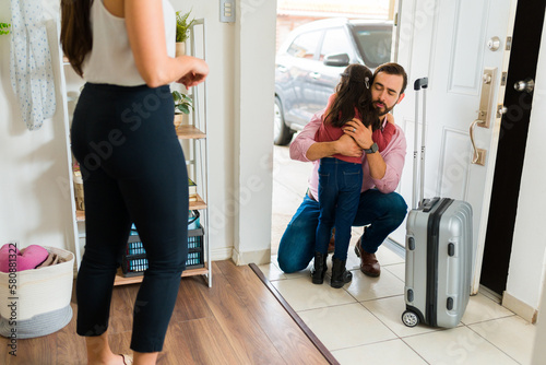 Upset young child hugging his dad before moving out
