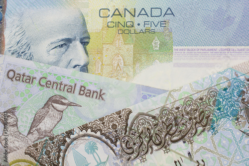 A colorful blue five dollar bill from Canada with colorful riyal notes from Qatar photo
