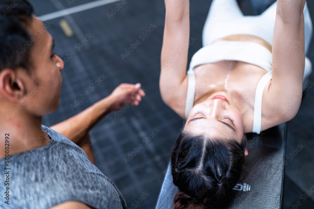 Obraz premium Top view Male fitness center instructor help woman lifting dumbbell workout at fitness center