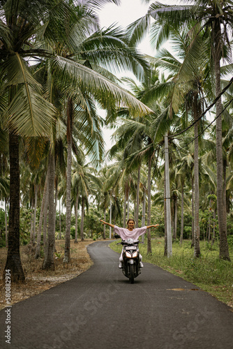 Young woman on a motorbike on the tropical island of Nusa Penida.