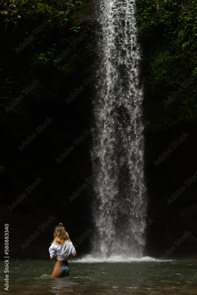 Fototapeta premium Woman tourist at a waterfall in the tropical jungle, Bali.