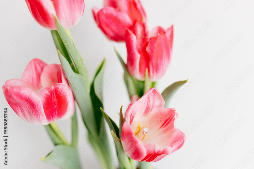 Pink tulips and engagement rings with diamonds on white background. Background for Valentine's Day. Gift for Mother's Day, international Women's Day, March 8th. Spring Mock ups. Space for text