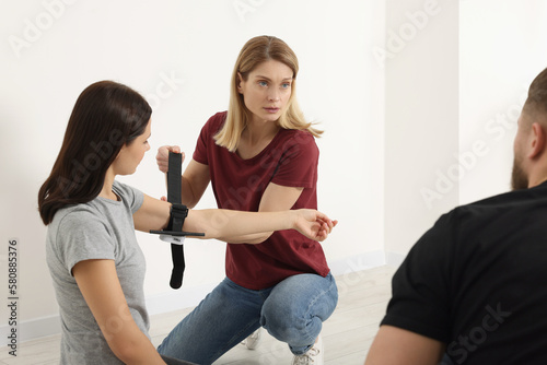 Group of people learning how to apply medical tourniquet on arm indoors