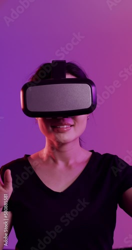Vertical video of asian woman and woman using vr headsets on purple background, slow motion photo