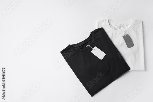 Stylish T-shirts with labels on white background, top view. Space for text