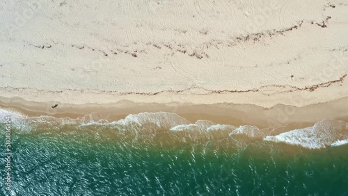 Bird's eye top aerial drone shot of the tropical Rio Grande do Norte, Brazil coastline with golden sand, turquoise clear water, and small calm waves in between Baia Formosa and Barra de Cunhaú photo