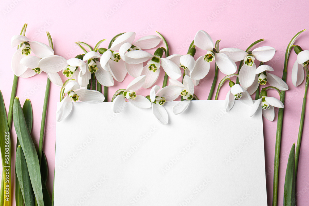 Obraz premium Beautiful snowdrops and paper card on pink background, flat lay. Space for text