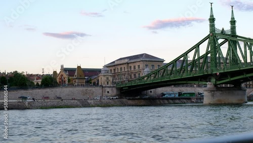 Wallpaper Mural Szabadság híd, Liberty or Freedom Bridge, in Budapest, Hungary. Danube River with boats and ferries, choppy water, tourists and cars, and golden hour clouds in sky - smooth cinematic 4k 30fps footage Torontodigital.ca