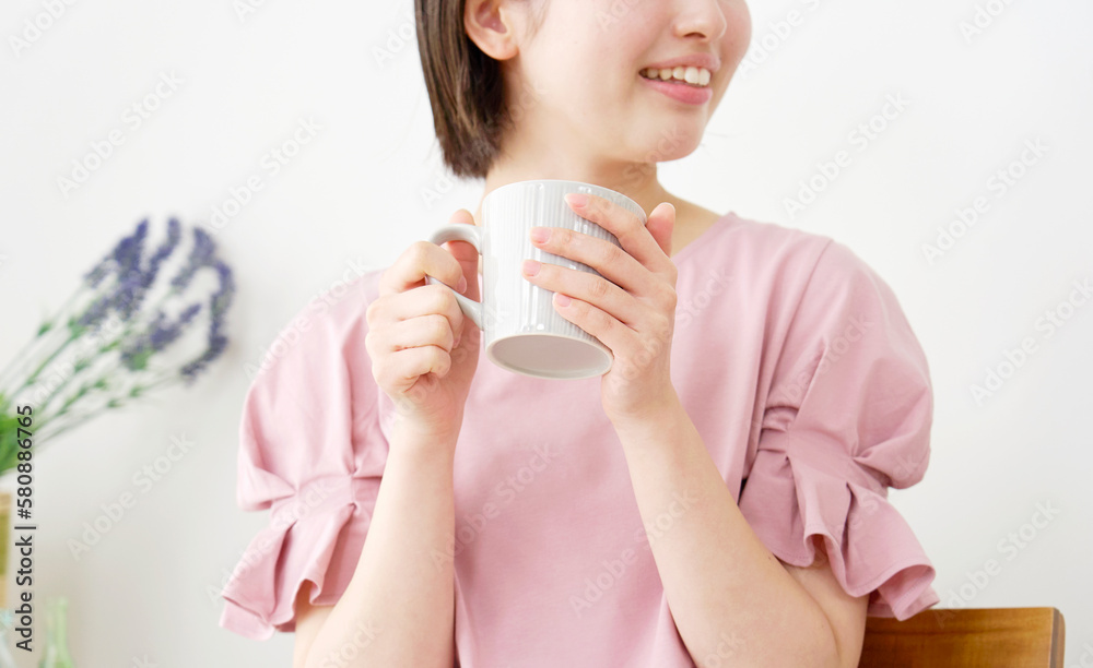 家で温かい飲み物を飲む女性の手元