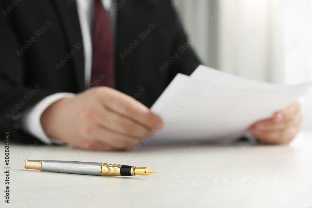 Notary reading documents at wooden table, focus on fountain pen - obrazy, fototapety, plakaty 