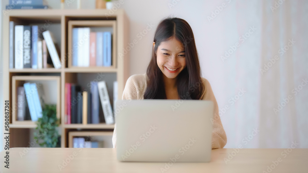 Young asian woman working at home. Female using computer laptop on desk at house Young asian woman working at home. Female using computer laptop on desk at house