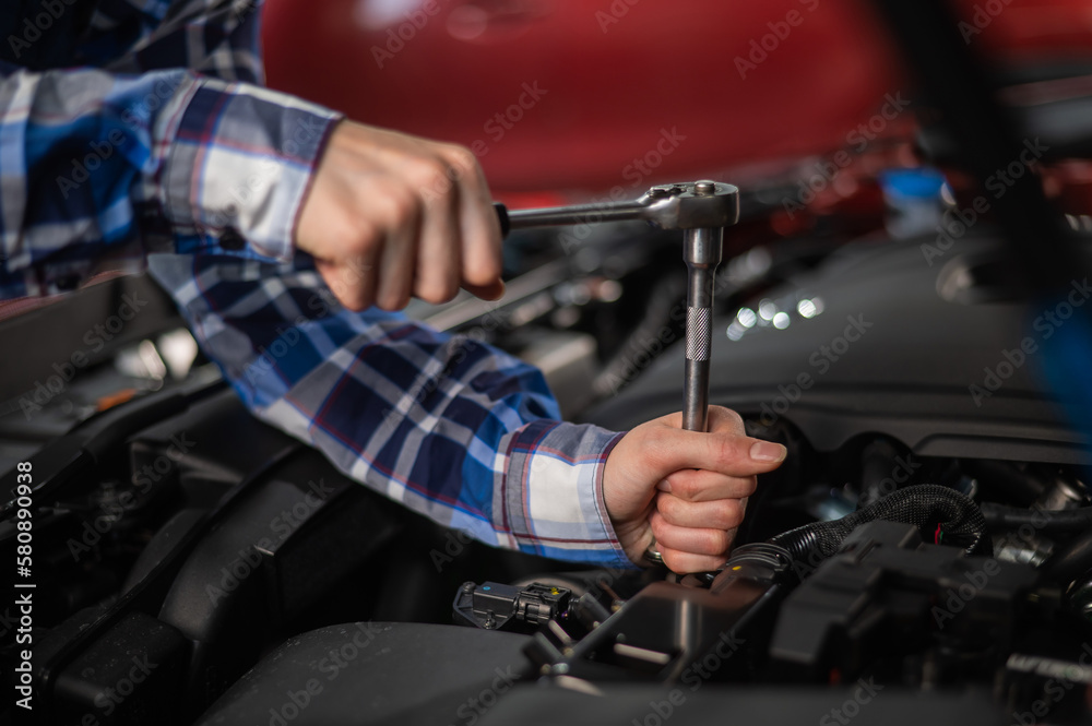Female auto mechanic unscrewing a nut to replace a car spark plug. Female auto mechanic unscrewing a nut to replace a car spark plug.