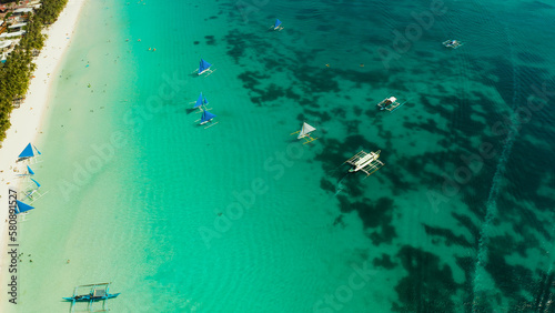Tropical lagoon with turquoise water, sailing yachts and white sand beach from above. Boracay, Philippines. White beach with tourists and hotels. Summer and travel vacation concept.
