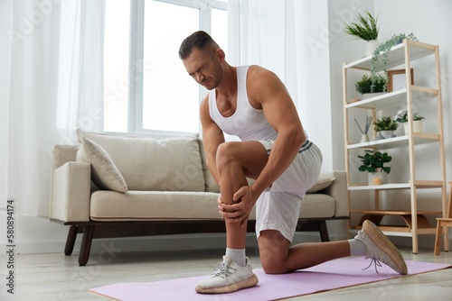 Man sports pain in the side and leg during a workout at home, pumped up man sports, the concept of health without injuries and sprains muscles and ligaments of the body
