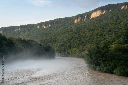 View of the Belaya River and the Una-koz ridge of the Caucasus Mountains in the background on a sunny summer day with clouds, Dakhovskaya, Republic of Adygea, Russia photo