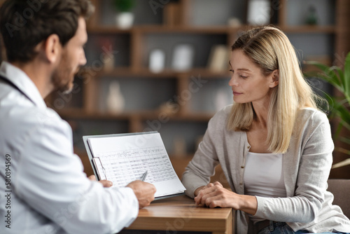 Doctor Man Showing Clipboard With Test Results To Curious Female Patient