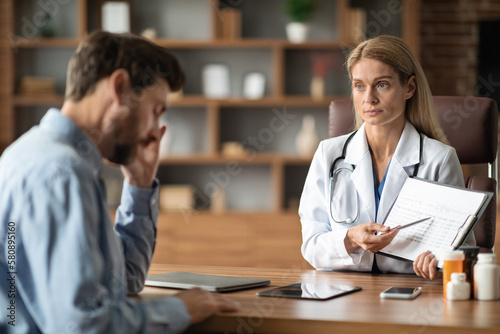 Doctor Showing Check Up Results To Male Patient During Meeting In Office