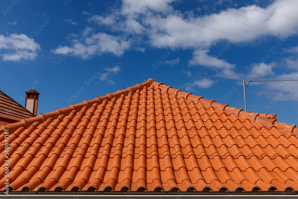 Red tiles panels roof under blue sky. Red tiles panels roof under blue sky.