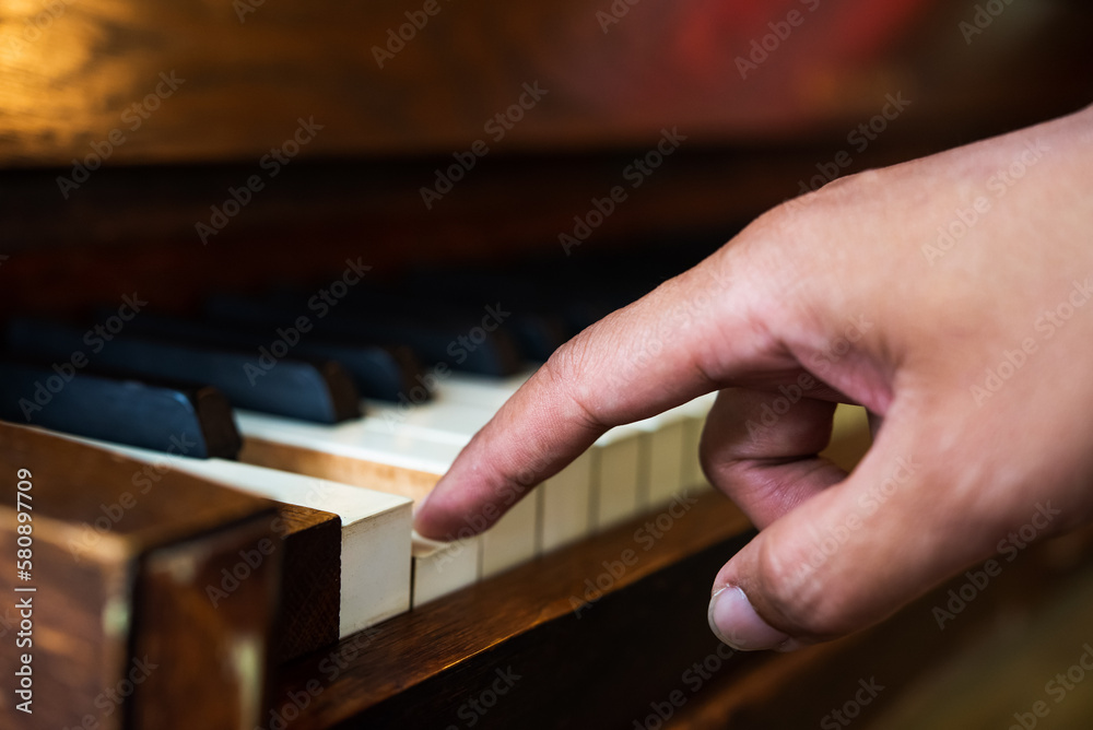 People Lifestyle: One finger touch on keyboard piano. Hand of Asian man test sound piano.  Musician paly old piano.  