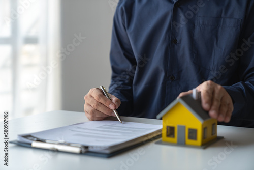 Young businessman, real estate insurance salesman reading and reviewing information Details of the agreement before signing the contract approval at home office investment and mortgage.